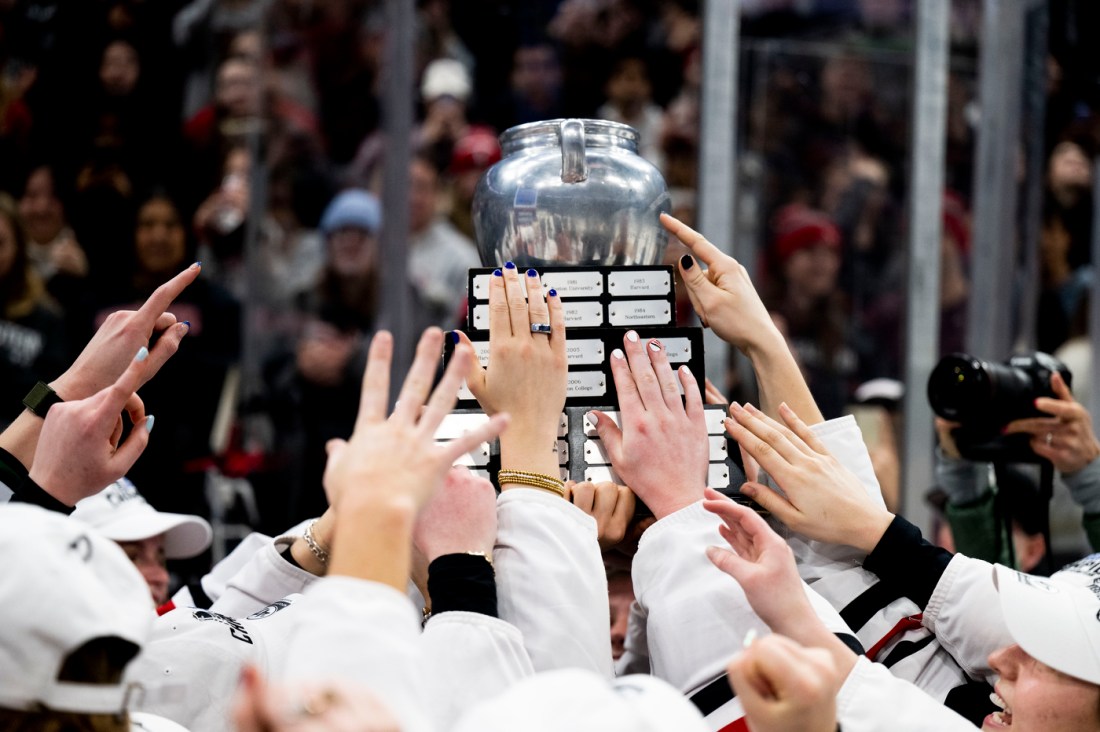 Many different hands reach for the beanpot trophy