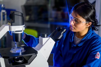 Cameron D'Mello sitting at a microscope.