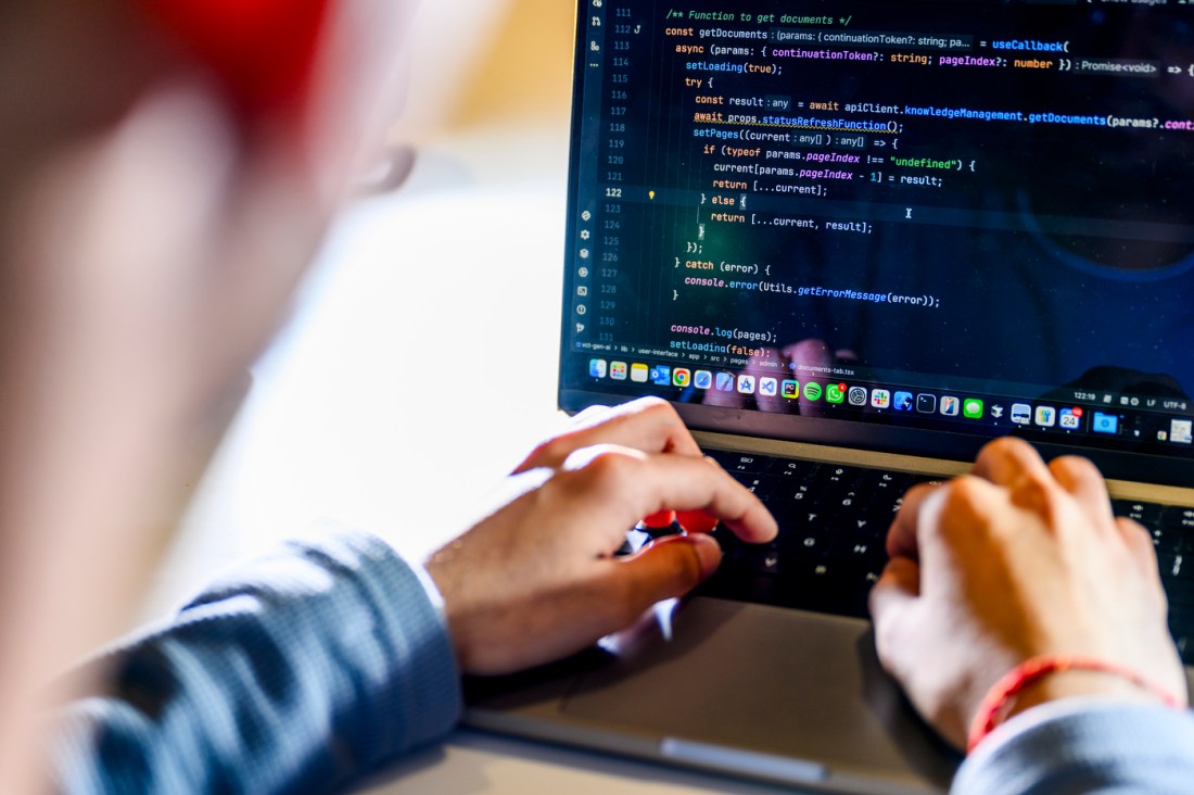 A student writing code on their laptop.