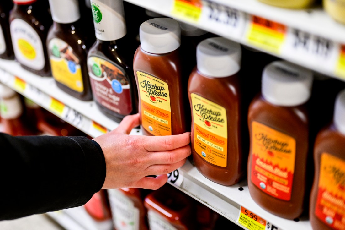 Jack Burns reaching for a bottle of 'Ketchup Please' on the shelf of Wollaston's grocer.