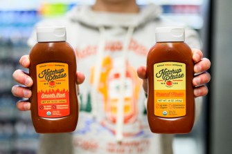 Jack Burns holding two bottles of 'Ketchup Please' ketchup.