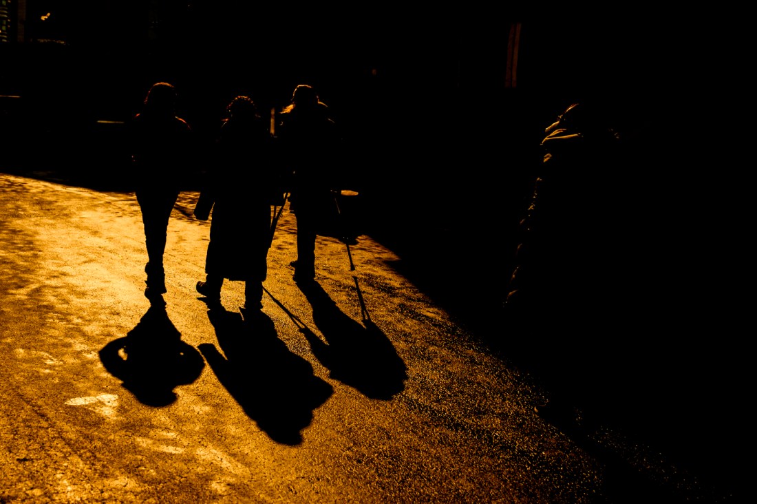 Students walk through Northeastern's Boston campus in the golden evening light, with a warm glow highlighting their silhouettes.