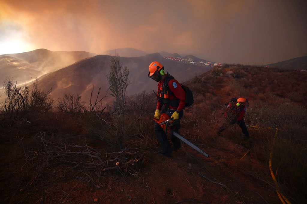 Firefighters standing on burnt expanses of ground in the LA area.