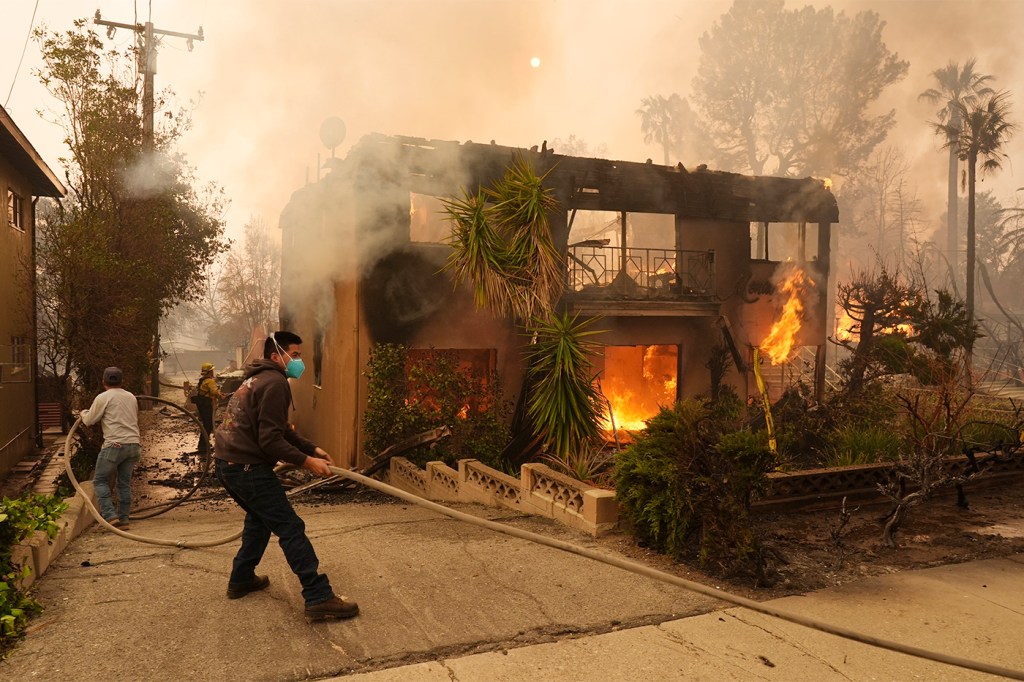 People helping a firefighter stretch a hose.