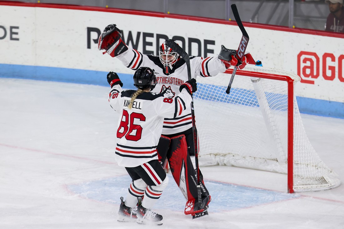 Lisa Jonsson on the ice in gear with her arms raised in celebration.