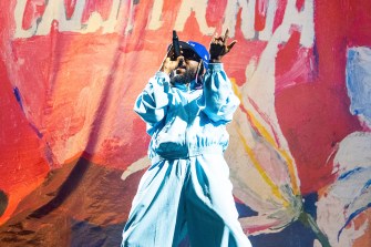 Kendrick Lamar rapping on stage wearing a blue coat and baseball jacket at Outside Lands Music festival.