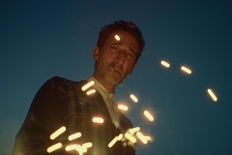 A screen capture of a character at night looking down at the camera as sparks fly across the screen.