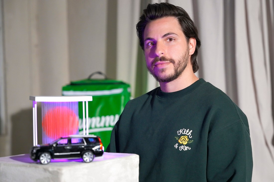 Portrait of Vicente Zavarce wearing a green sweatshirt next to a display with a model car on it.