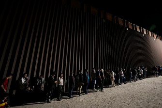 A line of immigrants at the border wall.