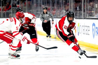 A Northeastern hockey player skating on the ice with the puck.