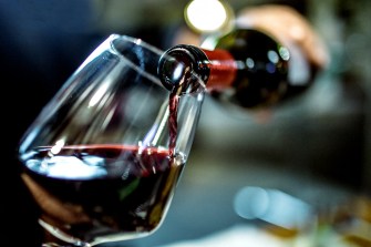 A person pouring a bottle of red wine into a glass.