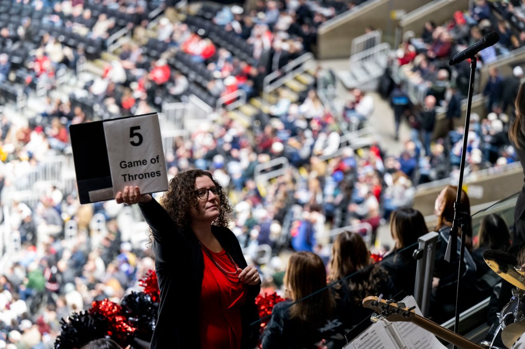 A conductor holds up a "5 Game of Thrones" music folder while leading Northeastern's pep band at the Beanpot semifinal.