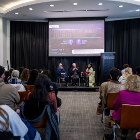 Denise Garcia, Ghaith al-Omari and Dennis Ross sitting on stage at the front of a room full of audience members listening to their fireside chat.