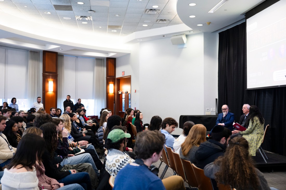 Dennis Ross, Ghaith al-Omari and Denise Garcia sitting on stage at the front of a room full of audience members sitting in rows.