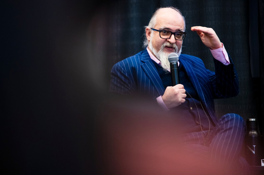 Ghaith al-Omari gesturing while speaking into a microphone on stage at the fireside chat.