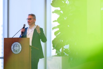 Tommaso Melodia wearing a suit standing at a podium speaking into a microphone at a conference.