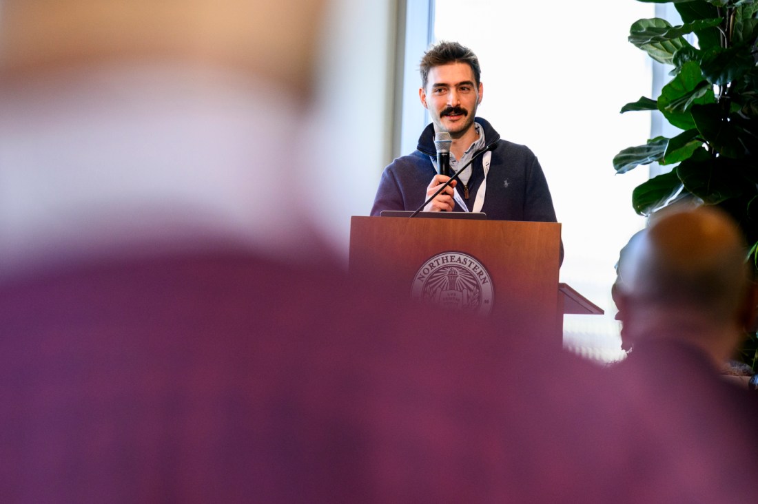 Paolo Testolina standing at a podium holding a microphone. 