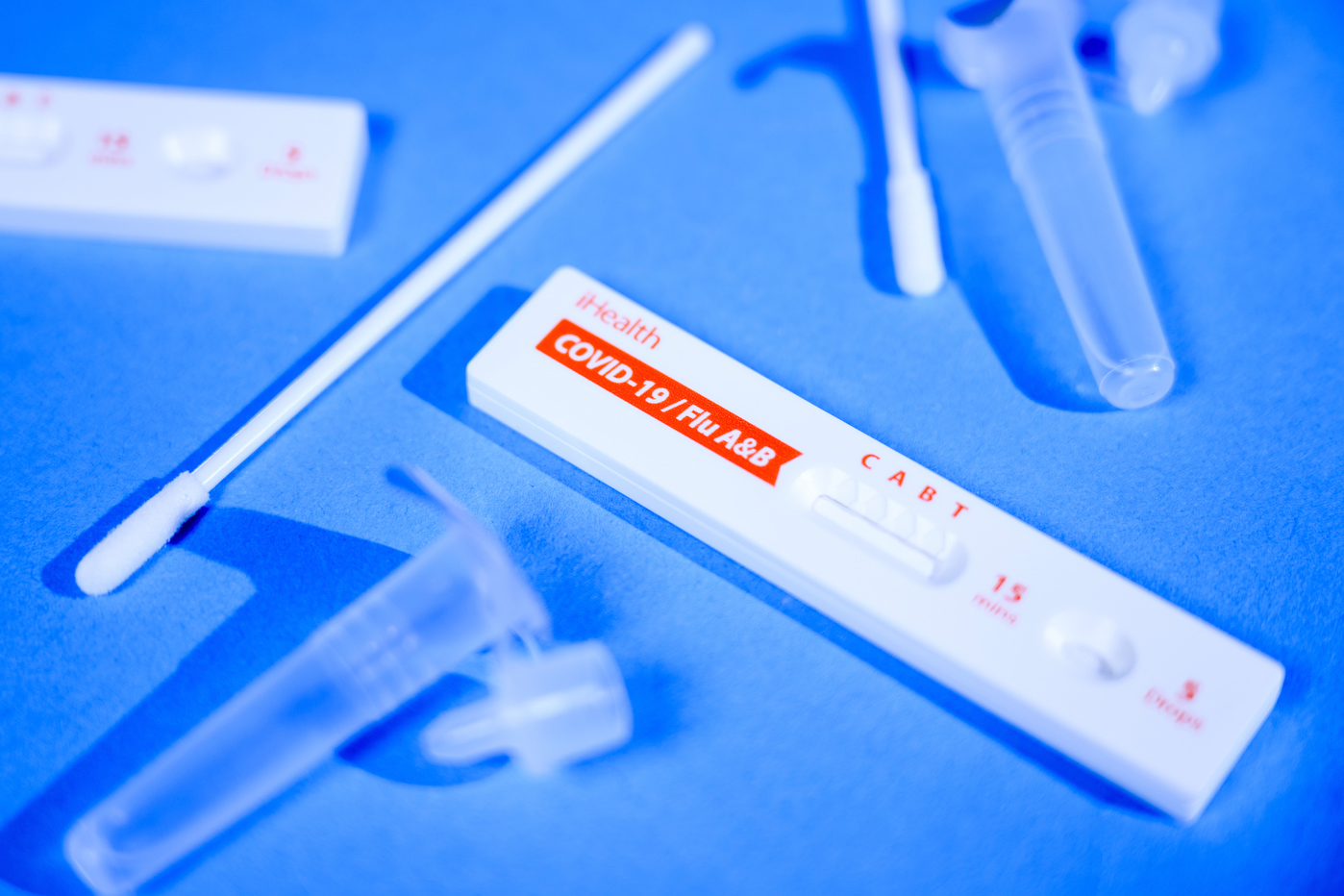 A COVID test kit lying out on a blue surface.