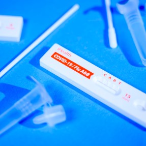A COVID test kit lying out on a blue surface.