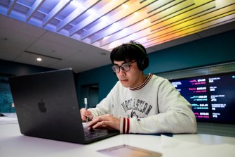 A person wearing headphones works on a laptop in a modern study space.