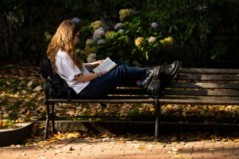 A person sitting on a bench reading a book.