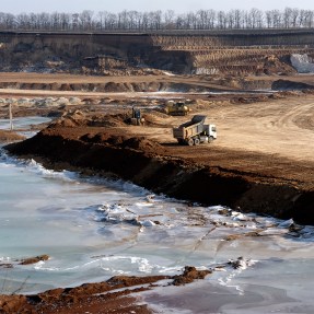 A truck parked on the edge of an ilmenite open pit mine in a canyon.