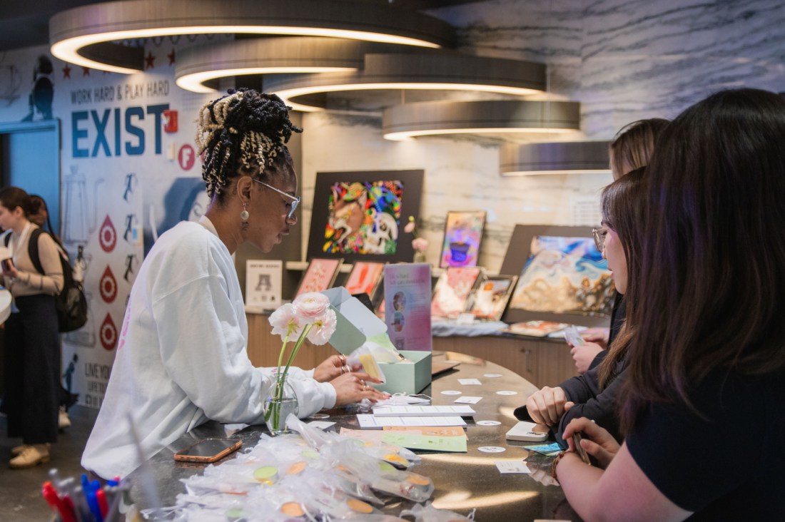 People gather around a desk at the WISE Summit. On the desk there are products laid out. 