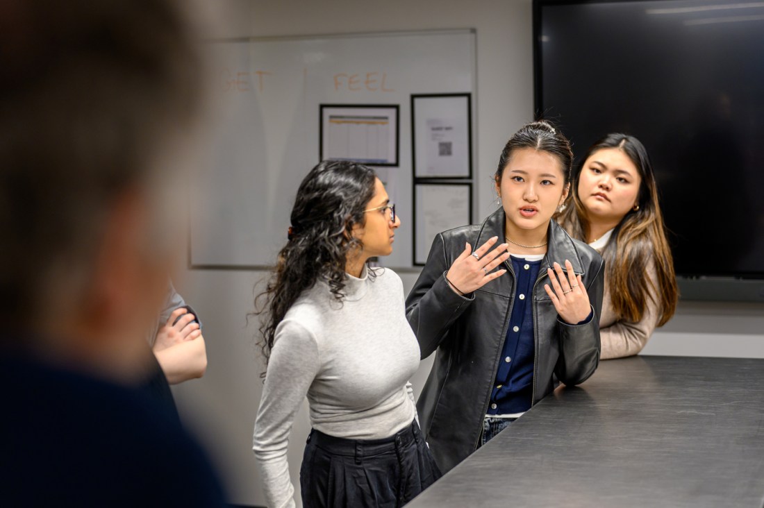 Three students standing together inside of a bakery chain headquarters.