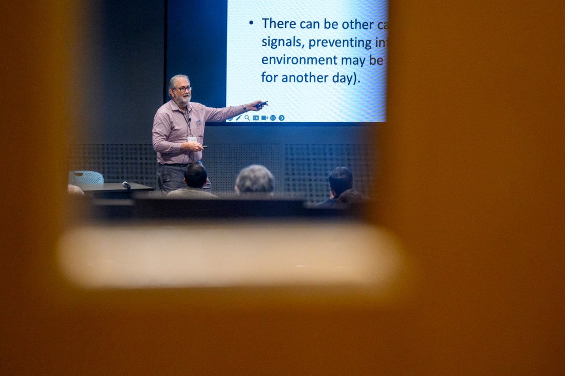 Herbert Levine standing in front of a screen pointing to a slide with black text on a white background.
