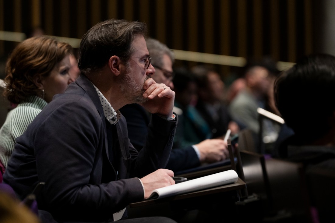 An audience member leaning forward with their hand against their month while listening intently to Ning Wang.