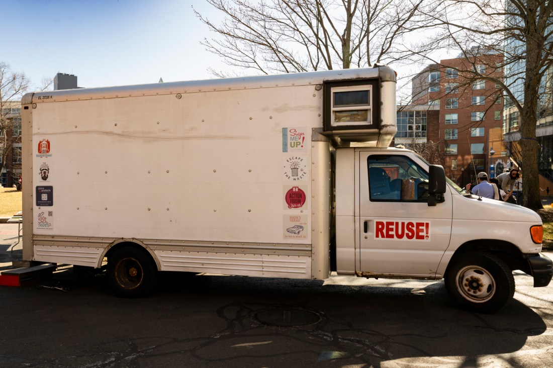 The exterior of a white box truck parked on Northeastern's Boston campus. There is a sticker that says 'REUSE!' on the outside.