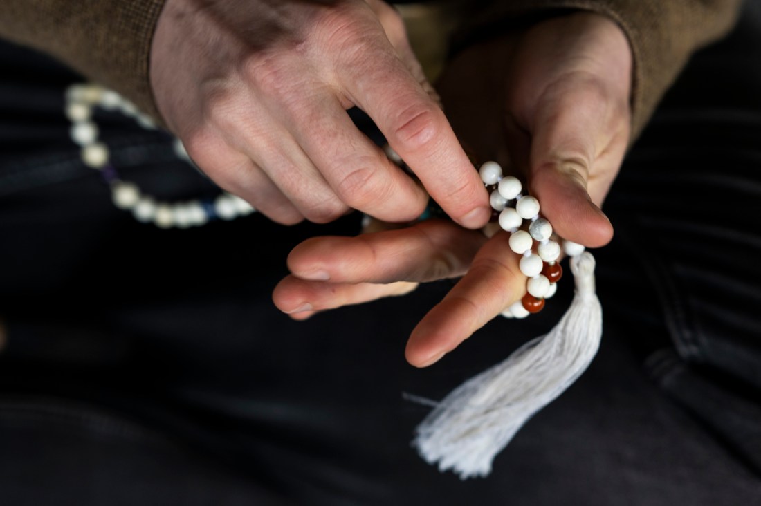 Evan Kenny's hands holding a singing bowl and prayer beads.