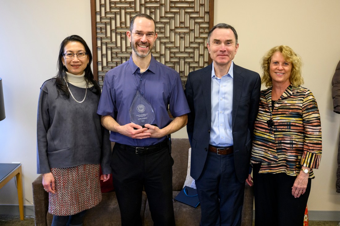 Kellee Tsai, Daniel Aldrich, and David Madigan and one other person posing for a photo. Daniel Aldrich is holding a glass award.