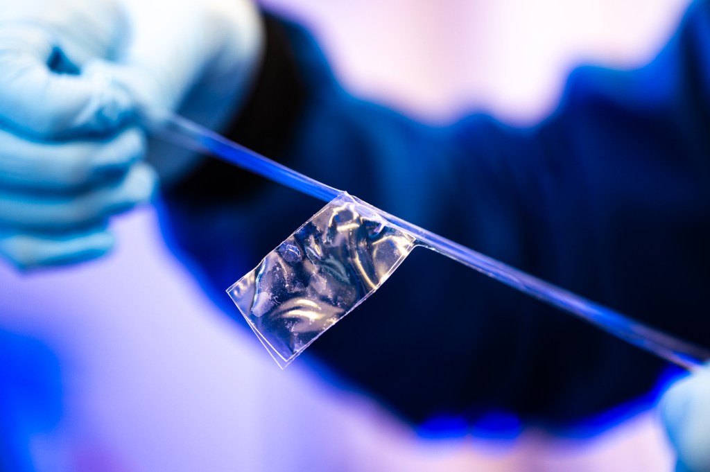 Ruobing Bai holding a piece of tape in the lab.