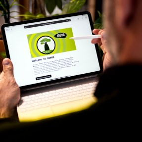 A person holding an iPad with a keyboard attached. It's open to a screen that says 'Welcome to Arbor' on it.