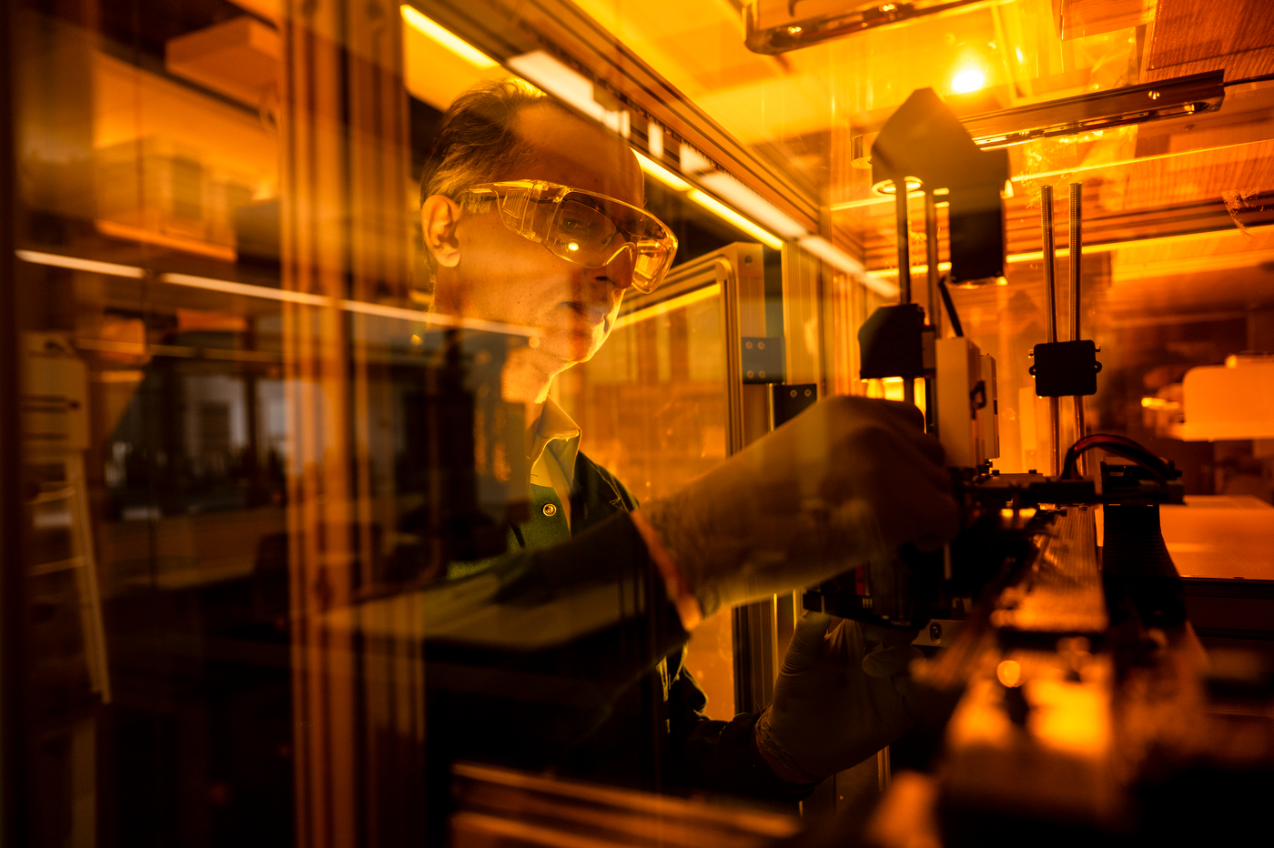Abraham Joy working in a lab that is lit by orange lighting.