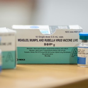Boxes and vials of the Measles vaccine on a table.