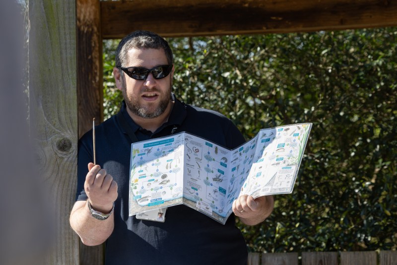 A person with sunglasses holding up a large pamphlet.