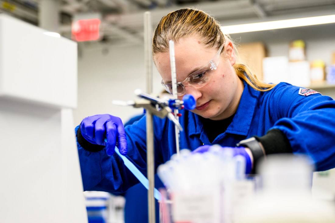 A student wearing a lab coat and goggles creating a cosmetic product.