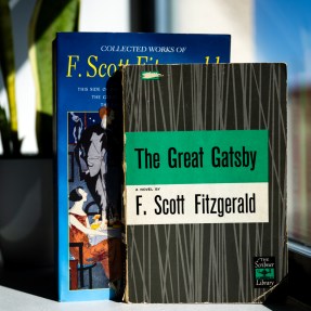 Two copies of The Great Gatsby with different covers standing up on a table.