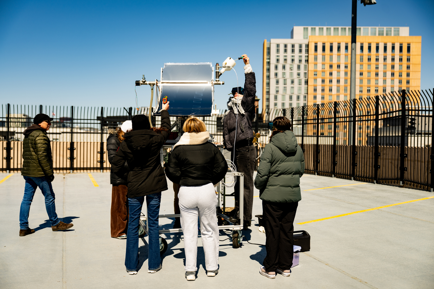 Students adjusting an engineering capstone project on the roof of a parking garage.