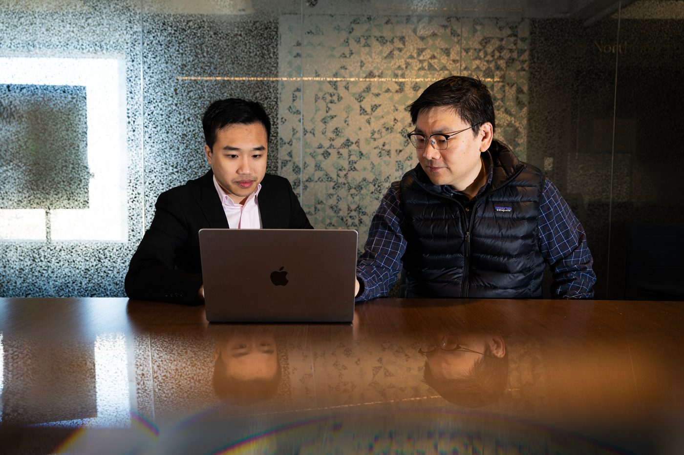 Anh Nguyen and Max Bi working side by side on one laptop.