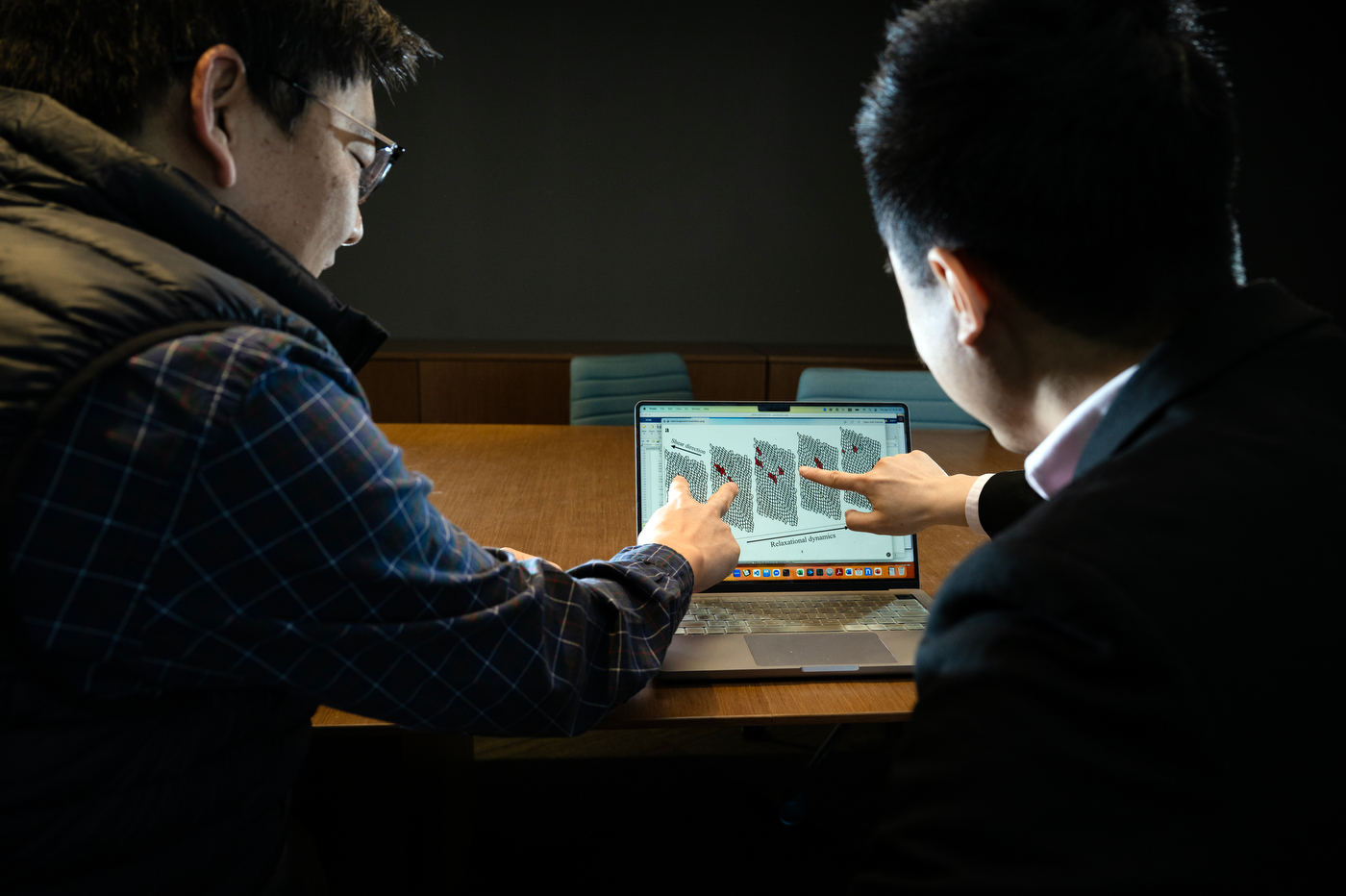 Anh Nguyen and Max Bi pointing to a graphic on a laptop.