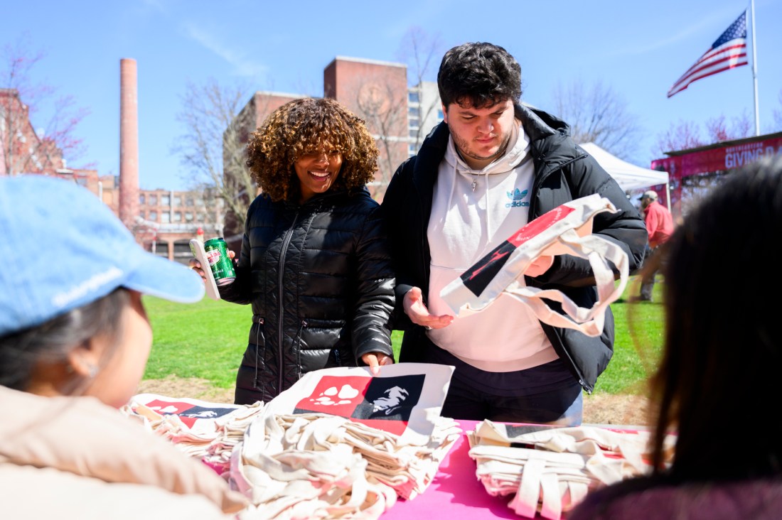 Two students looking at Northeastern branded merch at Giving Day 2025.