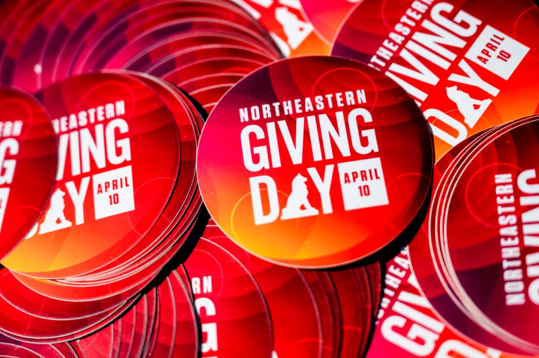 Piles of 'Northeastern Giving Day' branded stickers.
