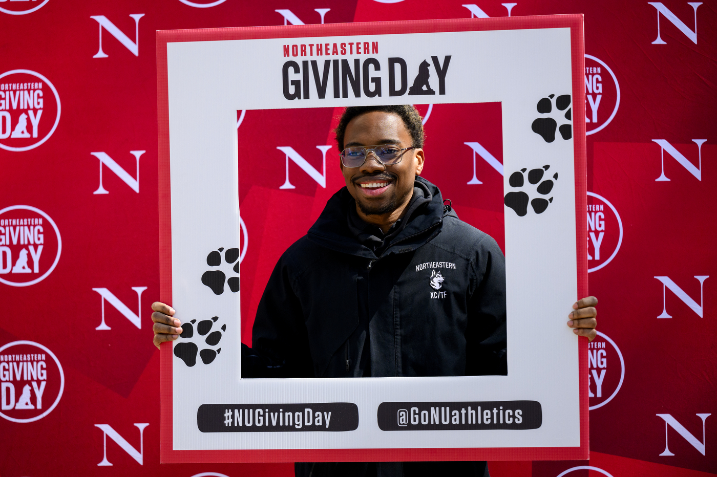 A student posing with a Giving Day branded photo frame.