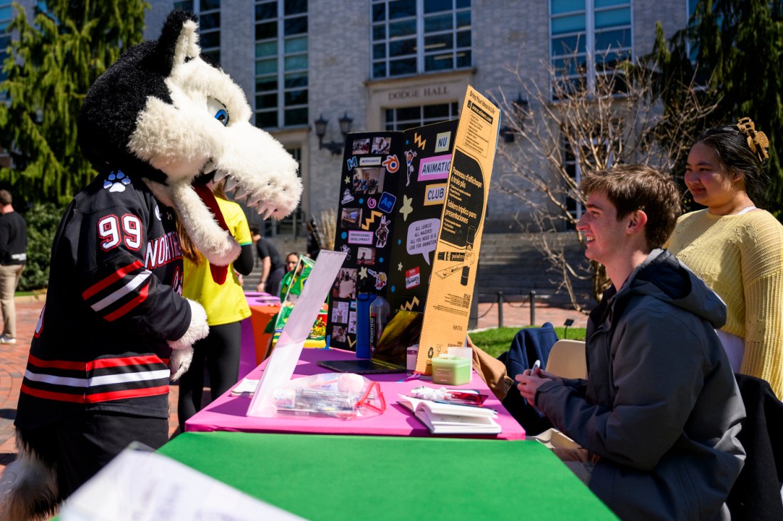 Paws standing in front two students tabling.