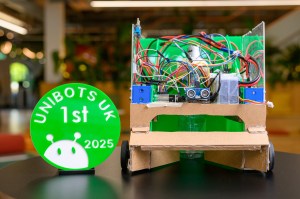 The robot of the two Northeastern students that won first prize at the Unibots competition next to a green medal saying 'Unibots UK 1st'.