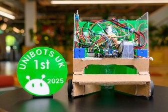 The robot of the two Northeastern students that won first prize at the Unibots competition next to a green medal saying 'Unibots UK 1st'.