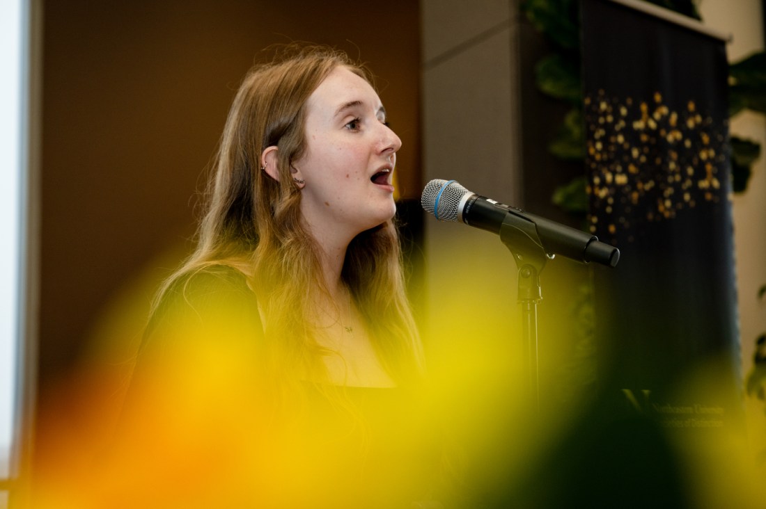 A member of the Northeastern community sings into a microphone at the Huntington 100 Induction Ceremony.
